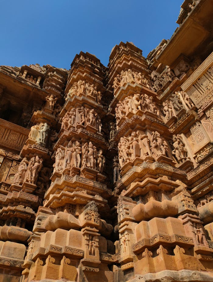Services Detailed view of ornate sandstone carvings on Khajuraho temple, showcasing ancient Indian architecture.